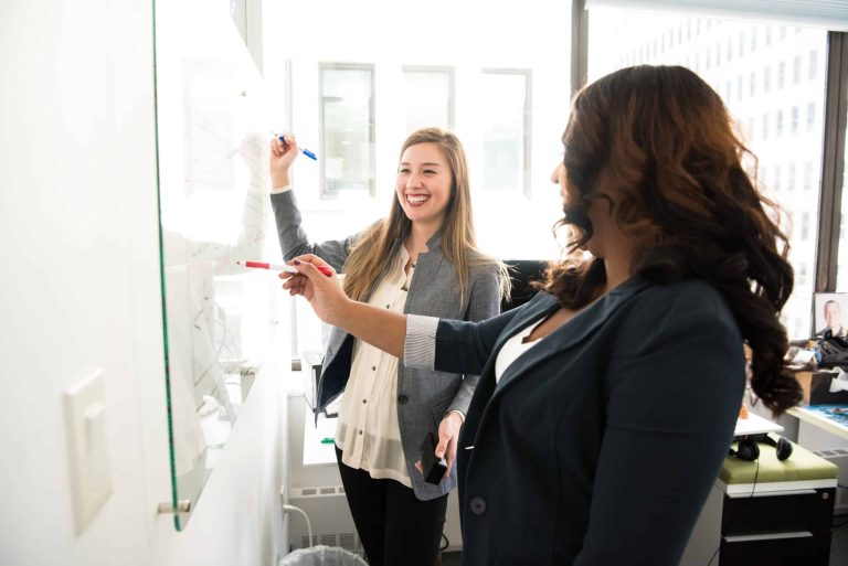 Healthcare professionals collaborating during a PET-CT training session, discussing imaging techniques and best practices on a whiteboard in a modern office setting