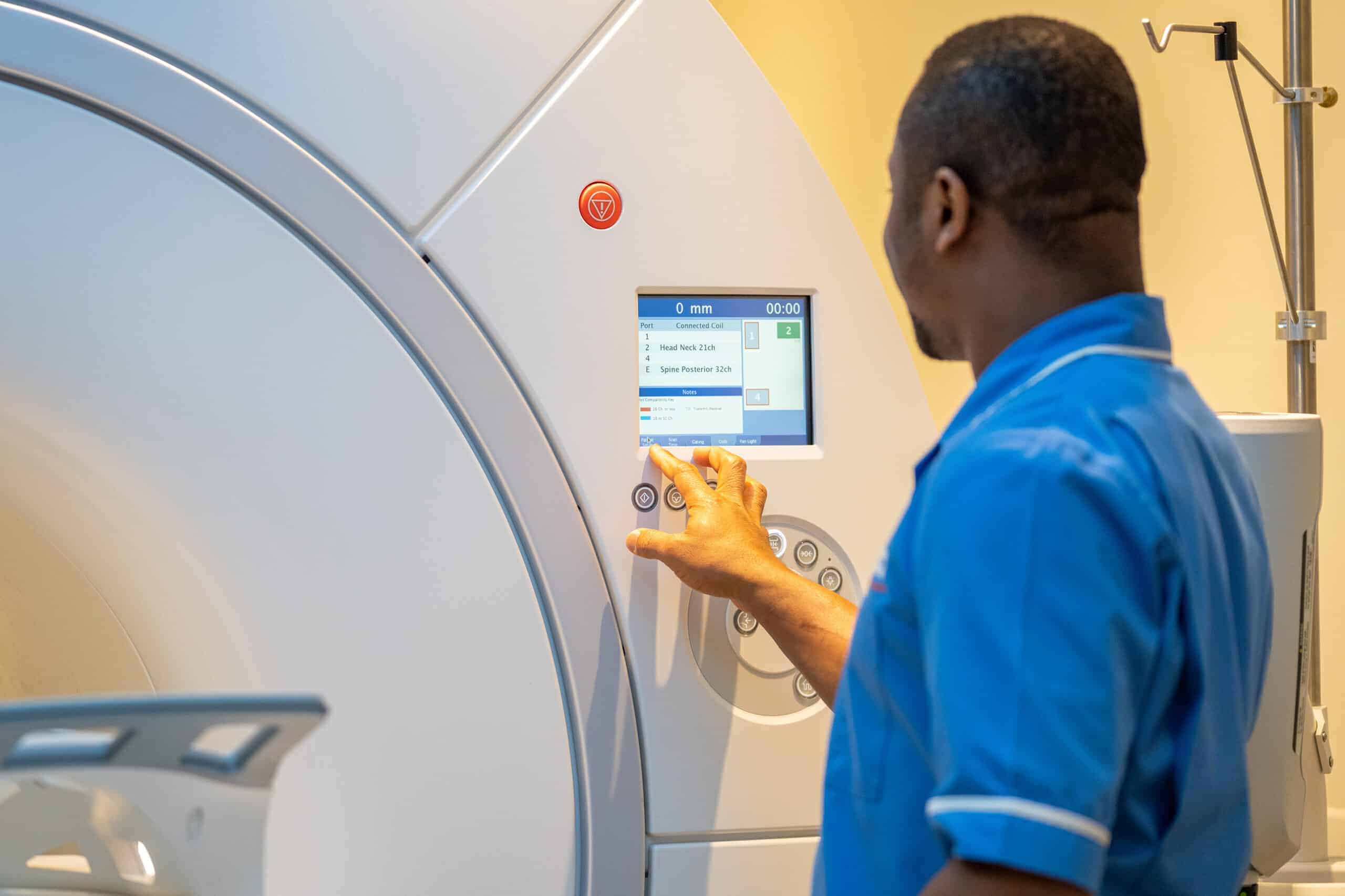 Medical professional operating a PET-CT scanner, adjusting settings on the machine’s control panel in a clinical environment.