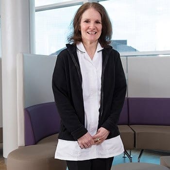 Skilled medical professional smiling in a modern clinical setting, highlighting expertise at The Christie PET-CT Academy.