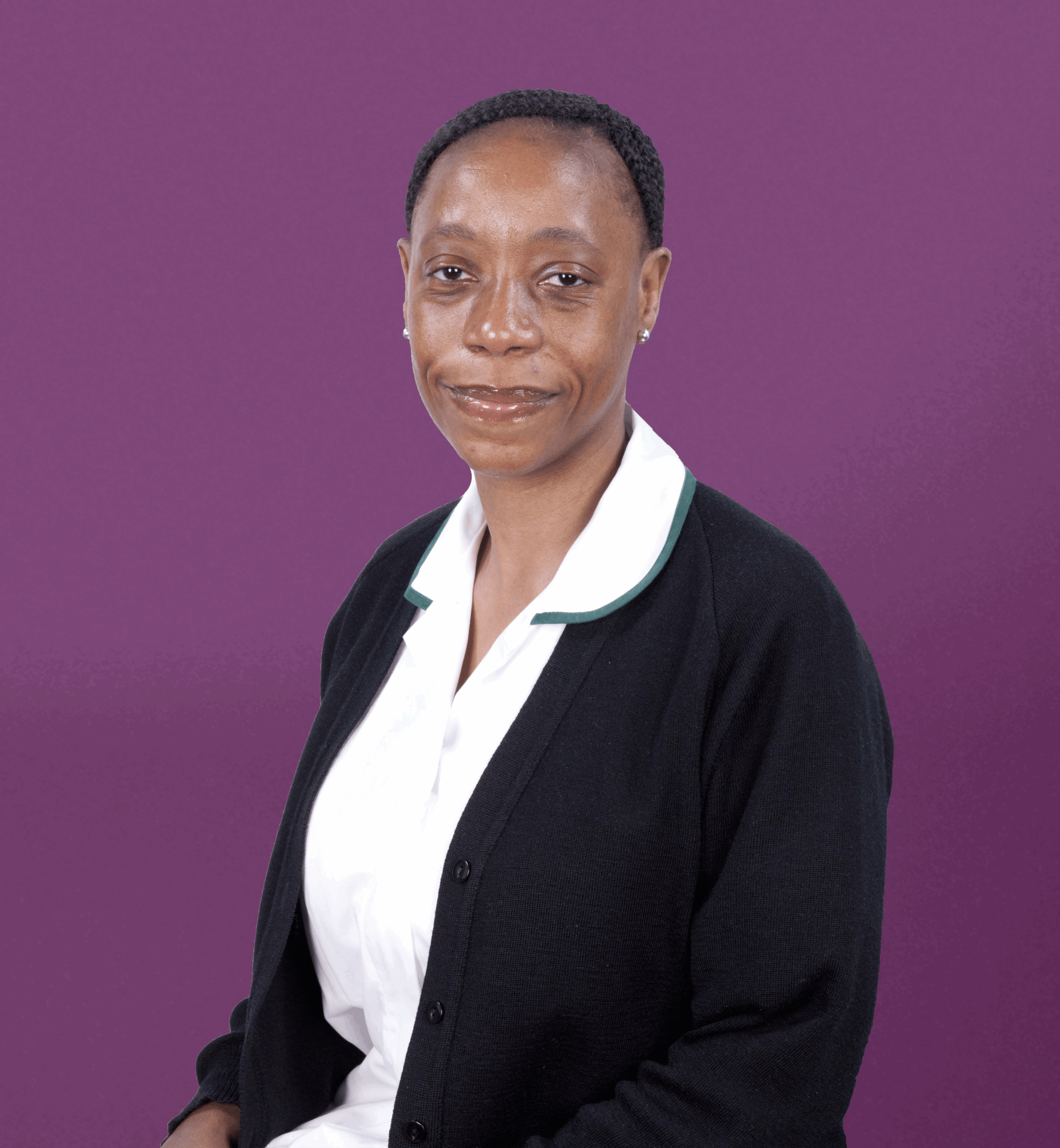 High-angle portrait of a professional woman in medical attire posing confidently against a purple background, representing The Christie PET-CT Academy’s focus on advanced imaging education and healthcare excellence.